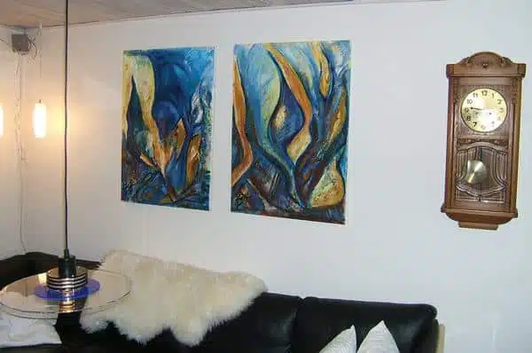 to solgte abstrakte malerier over sofaen. Der er i blå og gule farver