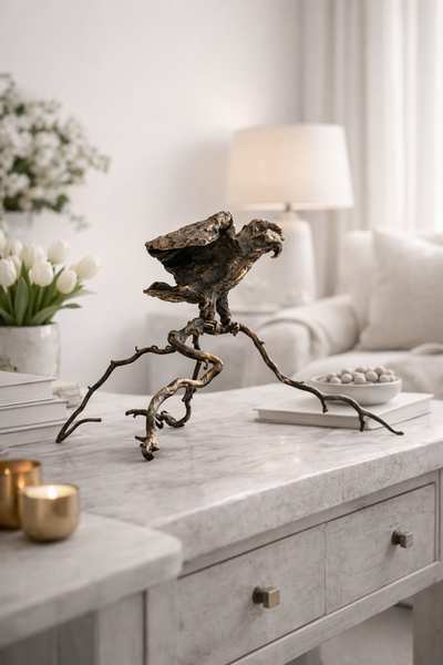 Bronzeskulptur af ørn på gren placeret på et bord i et lyst moderne hjem
